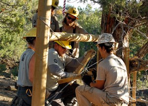 Southwest Conservation Corps crew members Sarah, Zoe, Aaron and Eric watch Jordan as he shows them how to twist staves in crossed wires to pull together an H-brace they installed in Spring Creek Basin's southeastern fence line.